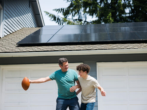 father and son playing basketball with panels on roof